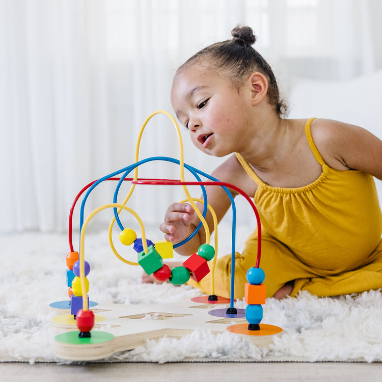 A kid playing with The Melissa & Doug Classic Bead Maze - Wooden Educational Toy