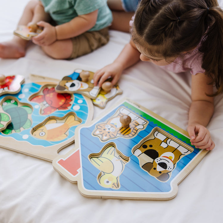 A kid playing with The Melissa & Doug Animals Jumbo Knob Wooden Puzzles Set - Fish and Pets