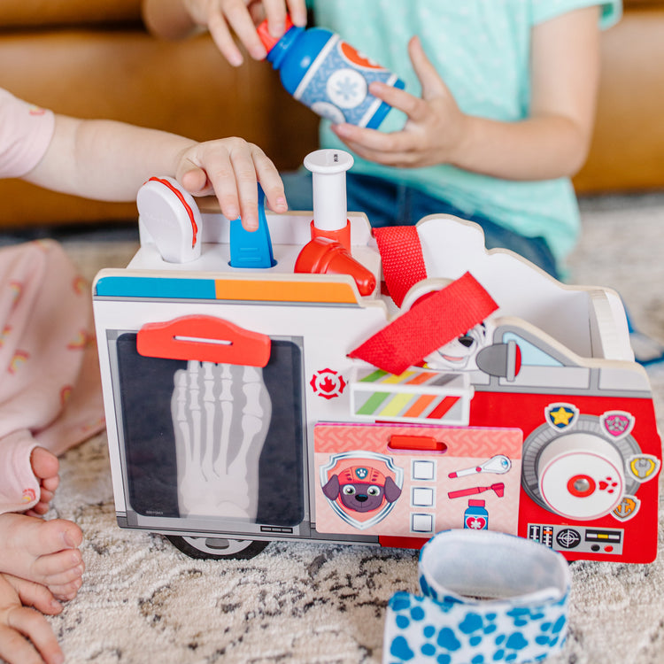 A kid playing with The Melissa & Doug PAW Patrol Marshall's Wooden Rescue EMT Caddy (14 Pieces)