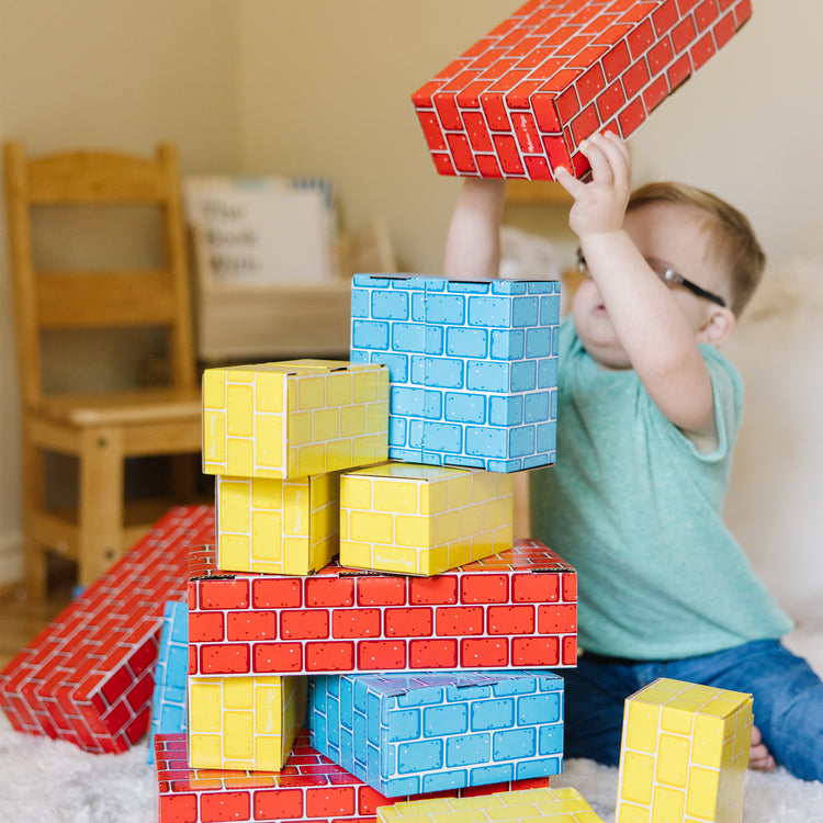 A kid playing with The Melissa & Doug Extra-Thick Cardboard Building Blocks - 24 Blocks in 3 Sizes