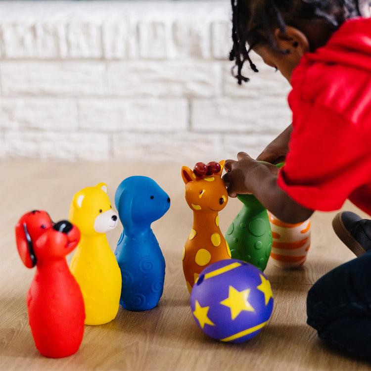 A kid playing with The Melissa & Doug K's Kids Bowling Friends Play Set and Game With 6 Pins and Convenient Carrying Case