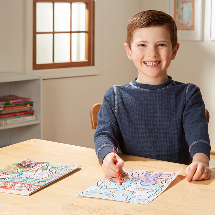 A kid playing with The Melissa & Doug My First Paint With Water Coloring Book: Animals (24 Painting Pages)