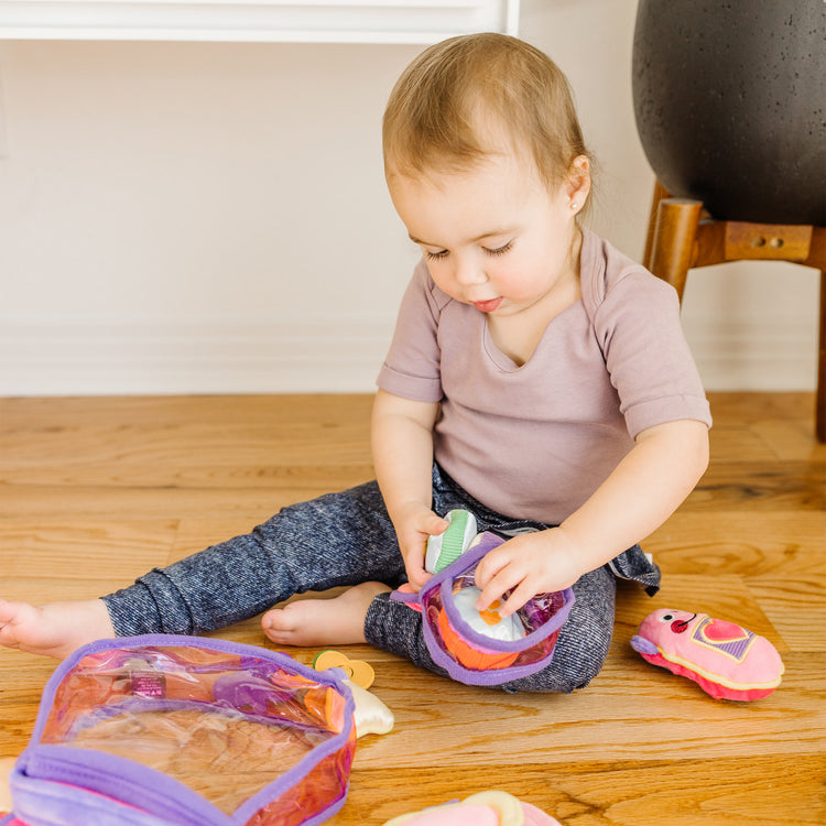 A kid playing with The Melissa & Doug Pretty Purse Fill and Spill Soft Play Set Toddler Toy