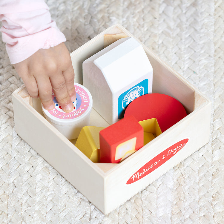 A kid playing with The Melissa & Doug Wooden Food Groups Play Food Set – Dairy