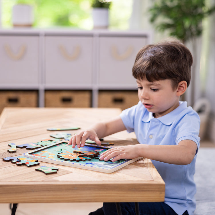 A kid playing with The Melissa & Doug Wooden Underwater Jigsaw Spinning Gear Puzzle – 18 Pieces