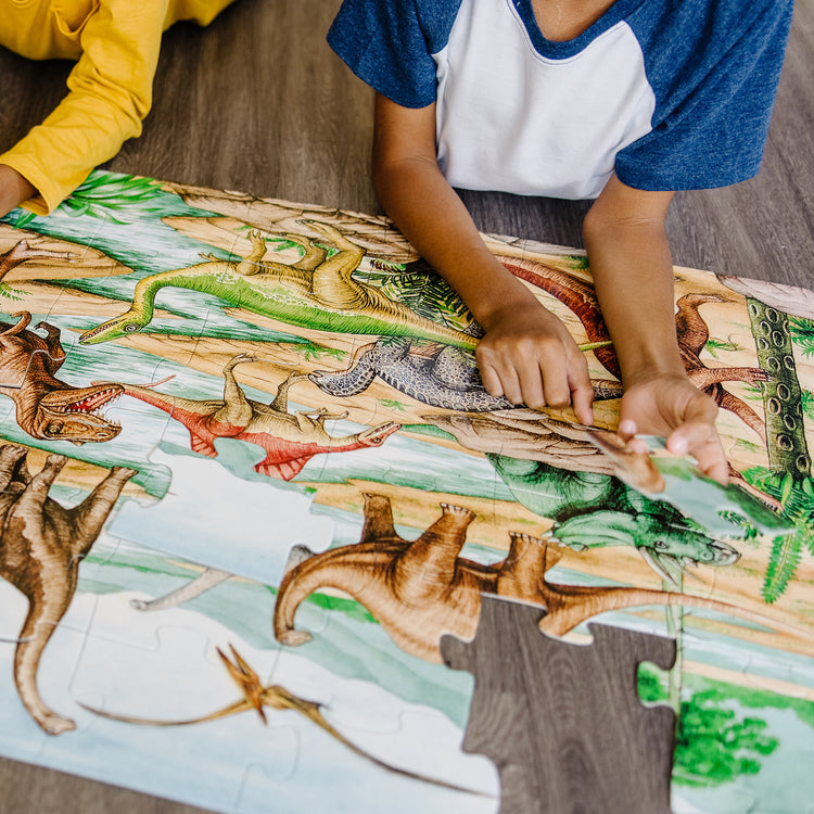 A kid playing with The Melissa & Doug Dinosaurs Floor Puzzle - 48 Pieces (2 Feet x 3 Feet Assembled)