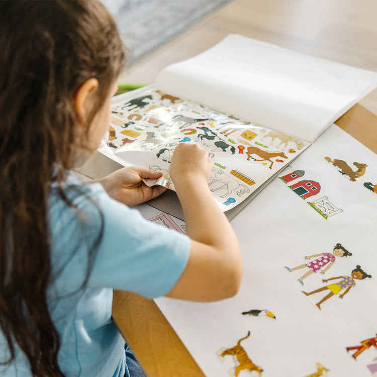 A kid playing with The Melissa & Doug Sticker Collection Book: Princesses, Tea Party, Animals, and More - 500+ Stickers