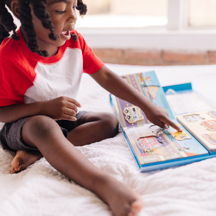 A kid playing with The Melissa & Doug To the Rescue Book and Wooden 6-Piece Puzzle Play Set