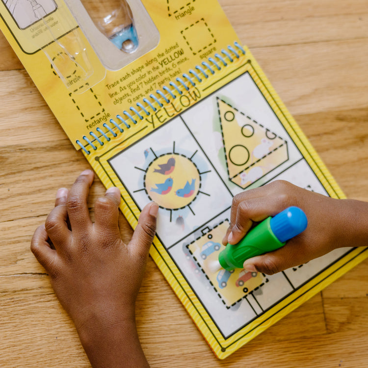 A kid playing with The Melissa & Doug On the Go Water Wow! Reusable Water-Reveal Activity Pad - Colors, Shapes