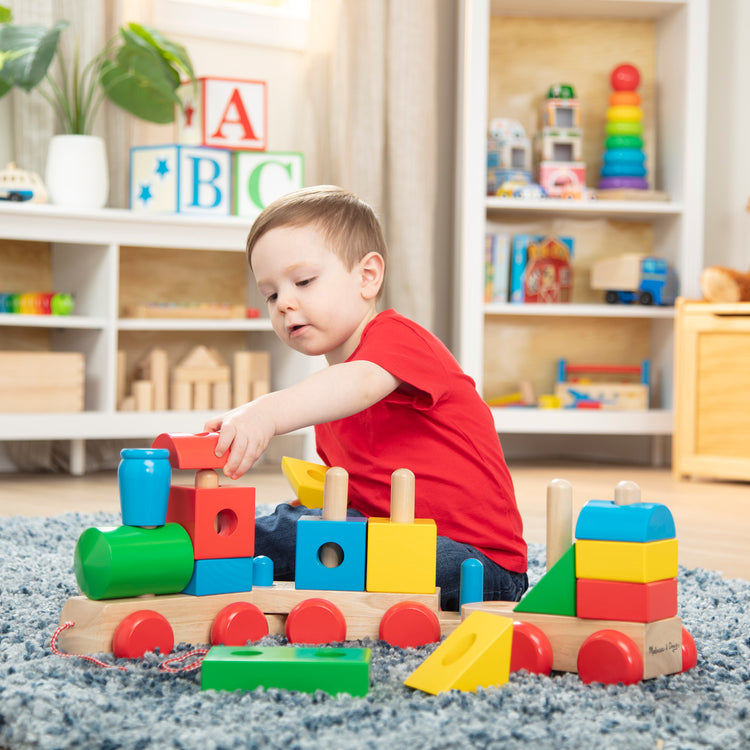 A kid playing with The Melissa & Doug Wooden Jumbo Stacking Train – 4-Color Classic Wooden Toddler Toy (17 pcs)