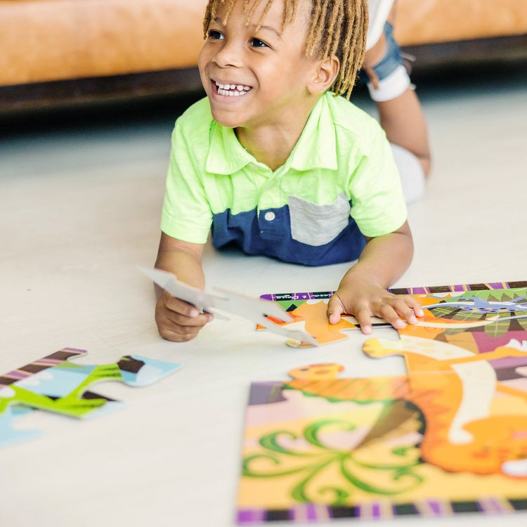 A kid playing with The Melissa & Doug Dinosaur Dawn Jumbo Jigsaw Floor Puzzle (24 pcs, 2 x 3 feet)