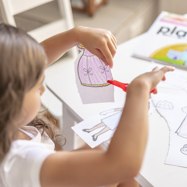 A kid playing with The Melissa & Doug Playmats Enchanted Kingdom Take-Along Paper Coloring And Learning Activity Pads (24 Pages)