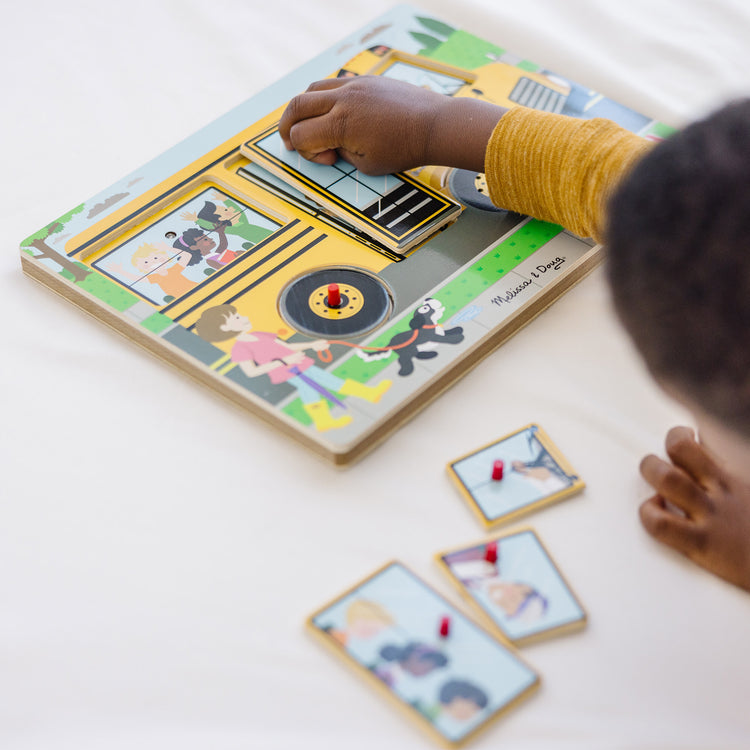 A kid playing with The Melissa & Doug The Wheels on the Bus Sound Puzzle