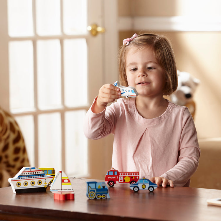 A kid playing with The Melissa & Doug Vehicles Wooden Chunky Puzzle - Plane, Train, Cars, and Boats (9 pcs)