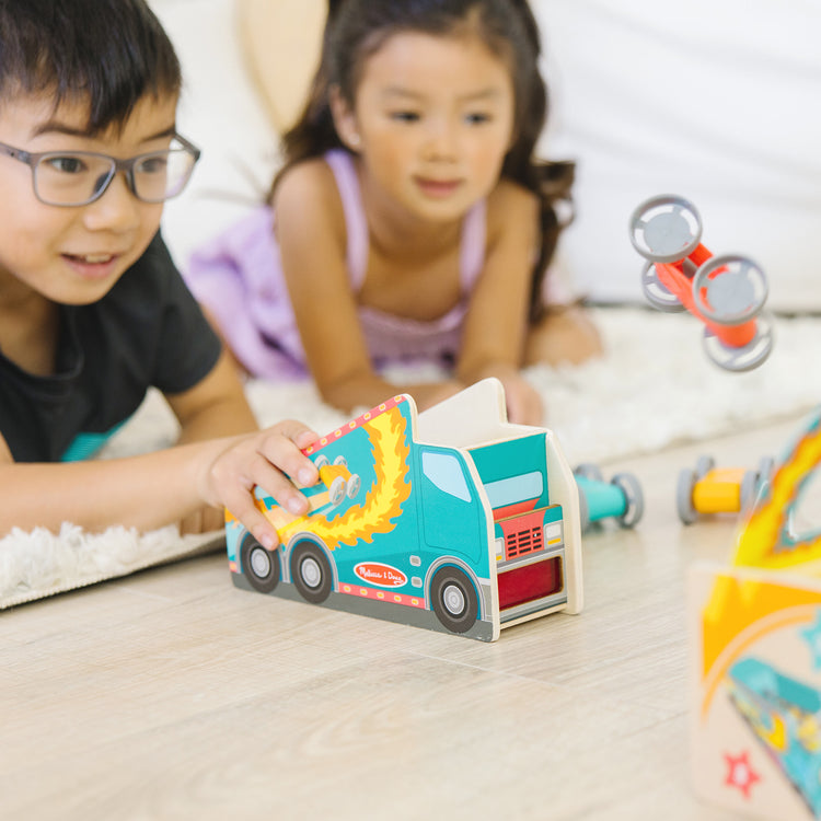 A kid playing with The Melissa & Doug Fun at the Fair! Wooden Ring of Fire Stunt Jumper Cars Game