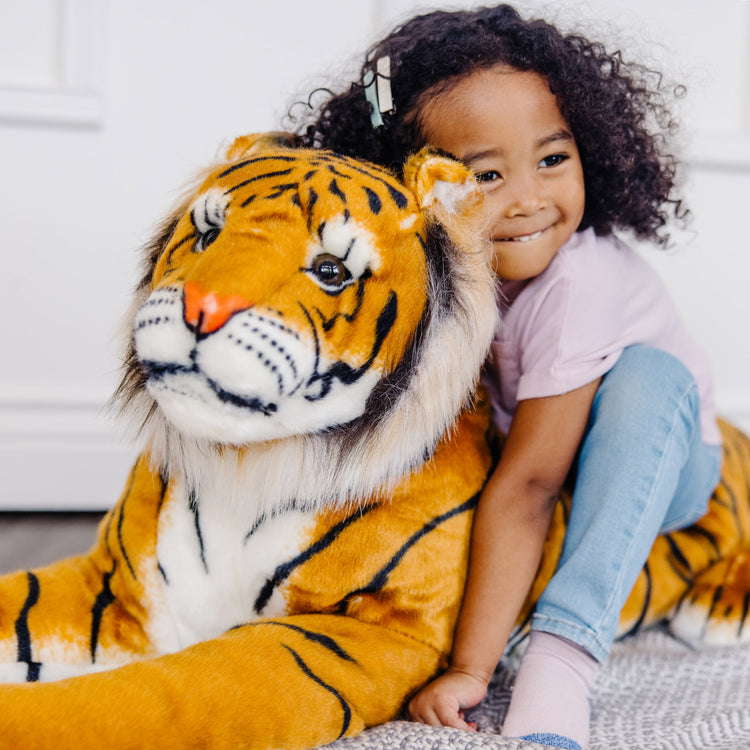 A kid playing with The Melissa & Doug Giant Tiger - Lifelike Stuffed Animal, Over 5 Feet Long (Includes Tail)