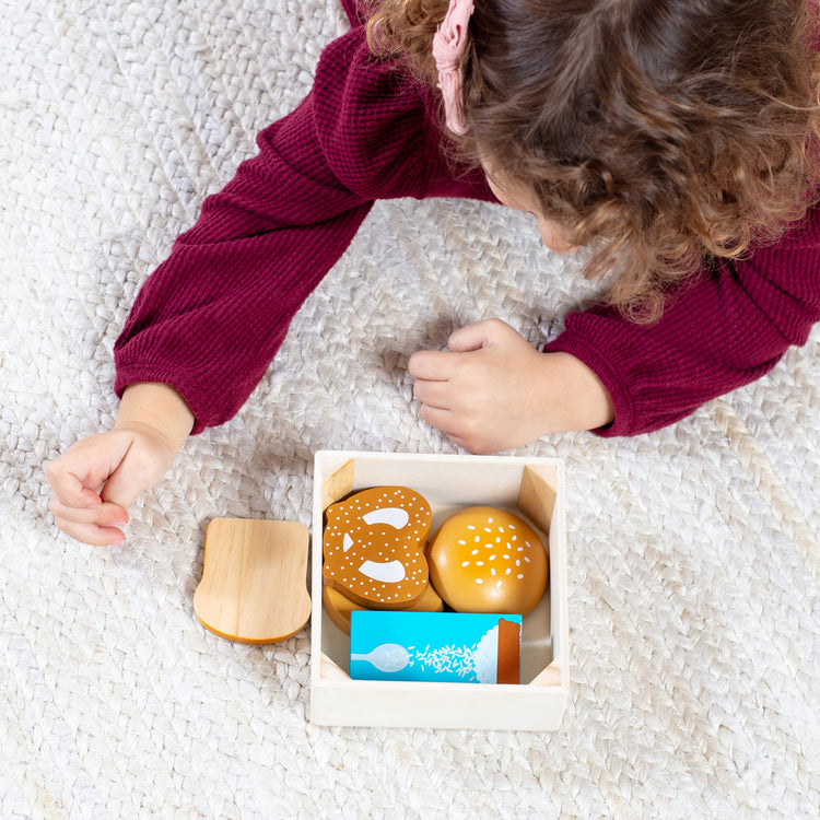 A kid playing with The Melissa & Doug Wooden Food Groups Play Food Set – Grains