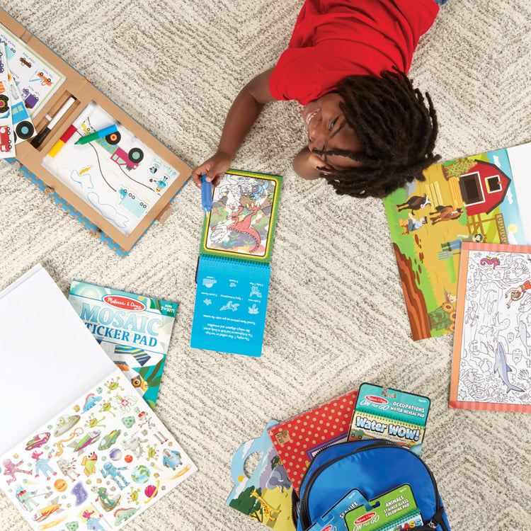 A kid playing with The Melissa & Doug Sticker Collection Book: Dinosaurs, Vehicles, Space, and More - 500+ Stickers