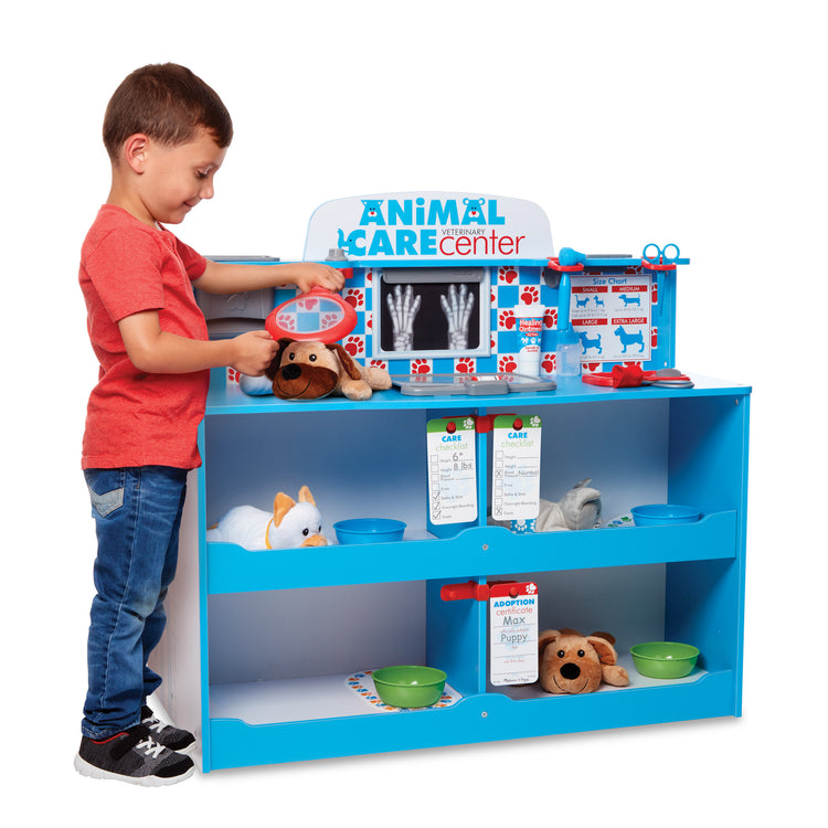 A child on white background with The Melissa & Doug Animal Care Veterinarian and Groomer Wooden Activity Center for Plush Stuffed Pets (Not Included)