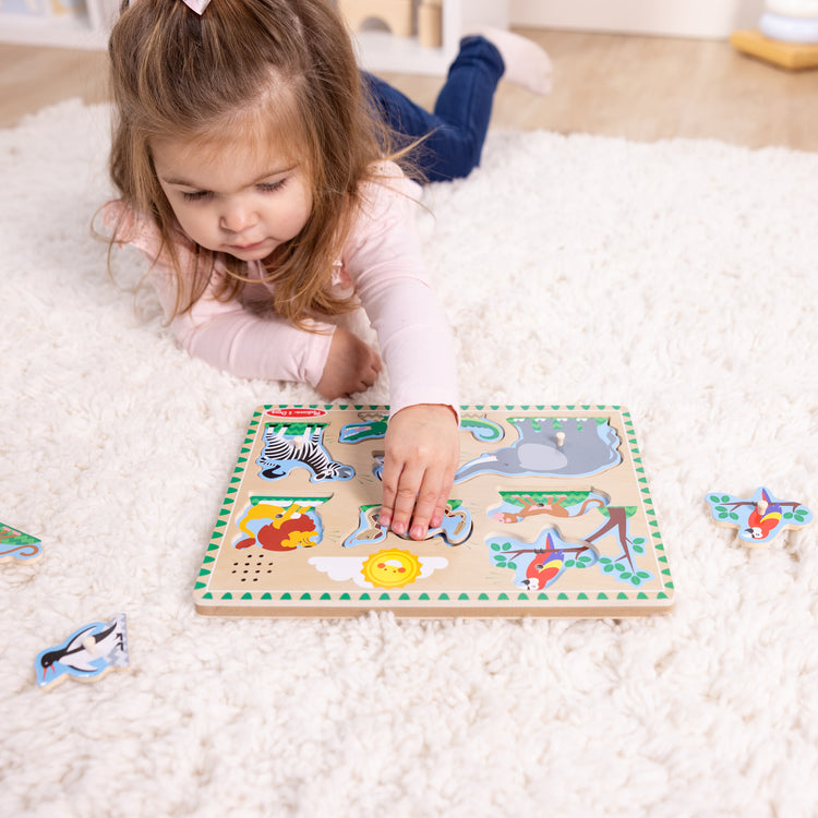 A kid playing with The Melissa & Doug Zoo Animals Sound Puzzle - Wooden Peg Puzzle With Sound Effects (8 pcs)