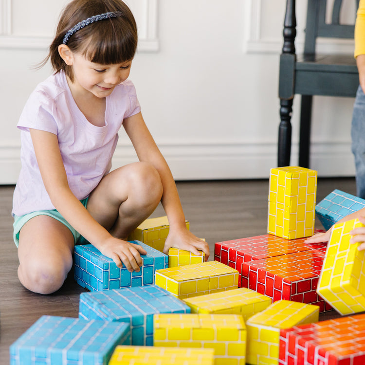 A kid playing with The Melissa & Doug Jumbo Extra-Thick Cardboard Building Blocks - 40 Blocks in 3 Sizes