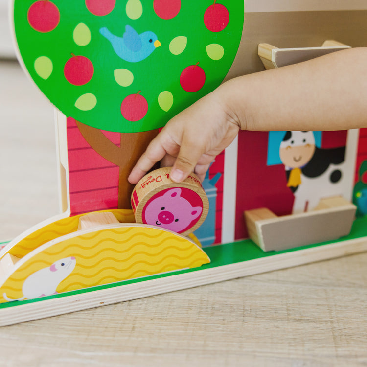 A kid playing with The Melissa & Doug GO Tots Wooden Barnyard Tumble with 4 Disks