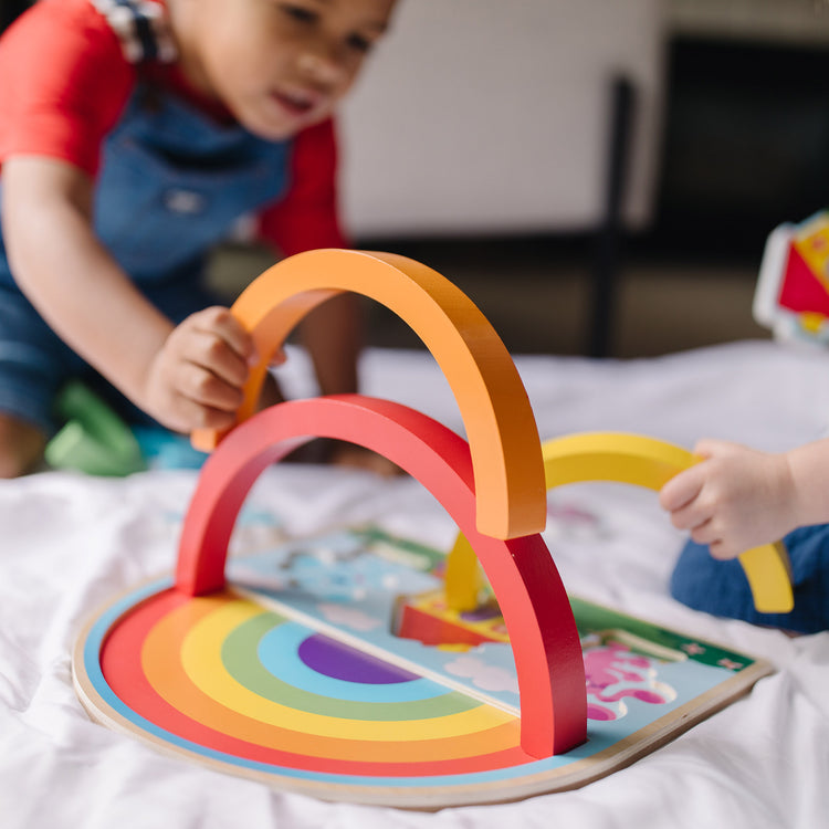 A kid playing with The Melissa & Doug Blue's Clues & You! Wooden Rainbow Stacking Puzzle (9 Pieces)