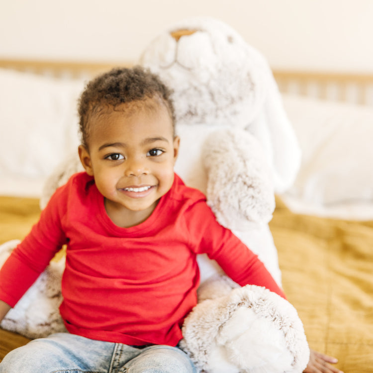 A kid playing with The Melissa & Doug Jumbo Burrow Bunny Lop-Eared Rabbit Stuffed Plush Animal (21 Inches Tall)