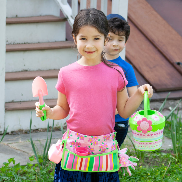 A kid playing with The Melissa & Doug Sunny Patch Pretty Petals Flower Watering Can - Pretend Play Toy