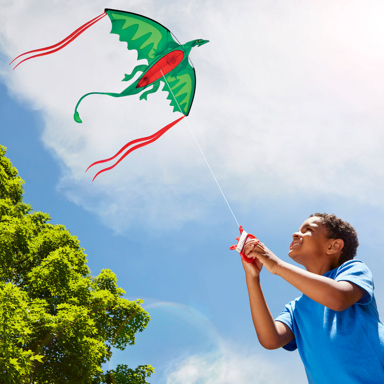 A kid playing with The Melissa & Doug Winged Dragon Shaped Kite (62-Inch Wingspan)