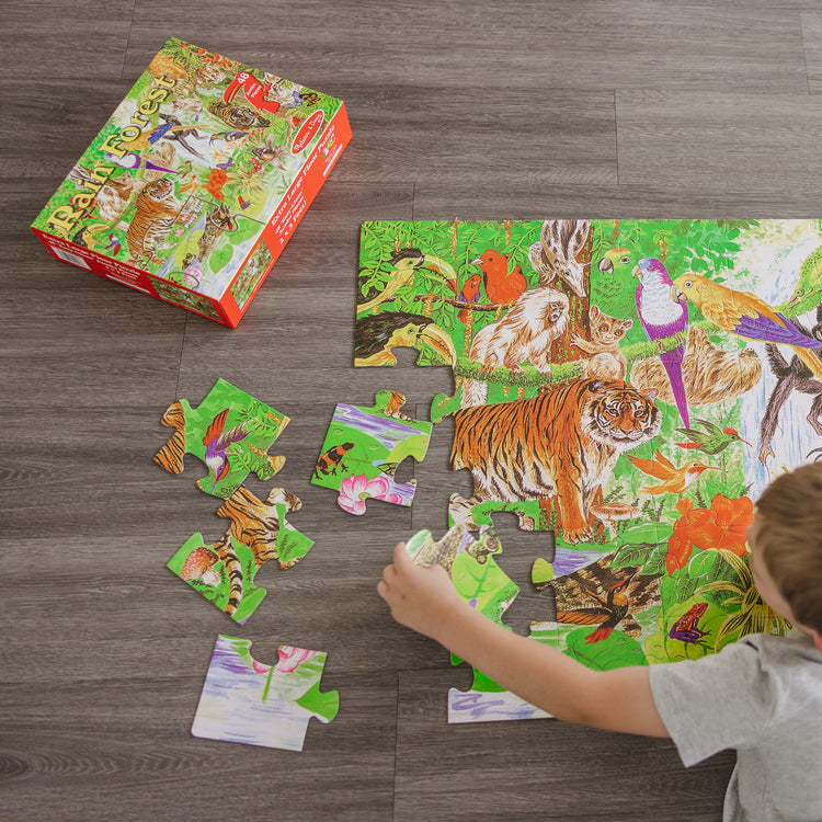 A kid playing with The Melissa & Doug Rainforest Floor Puzzle (48 pcs, 2 x 3 feet)