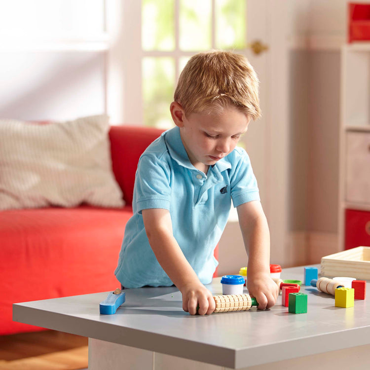 A kid playing with The Melissa & Doug Clay Play Activity Set - With Sculpting Tools and 8 Tubs of Modeling Dough