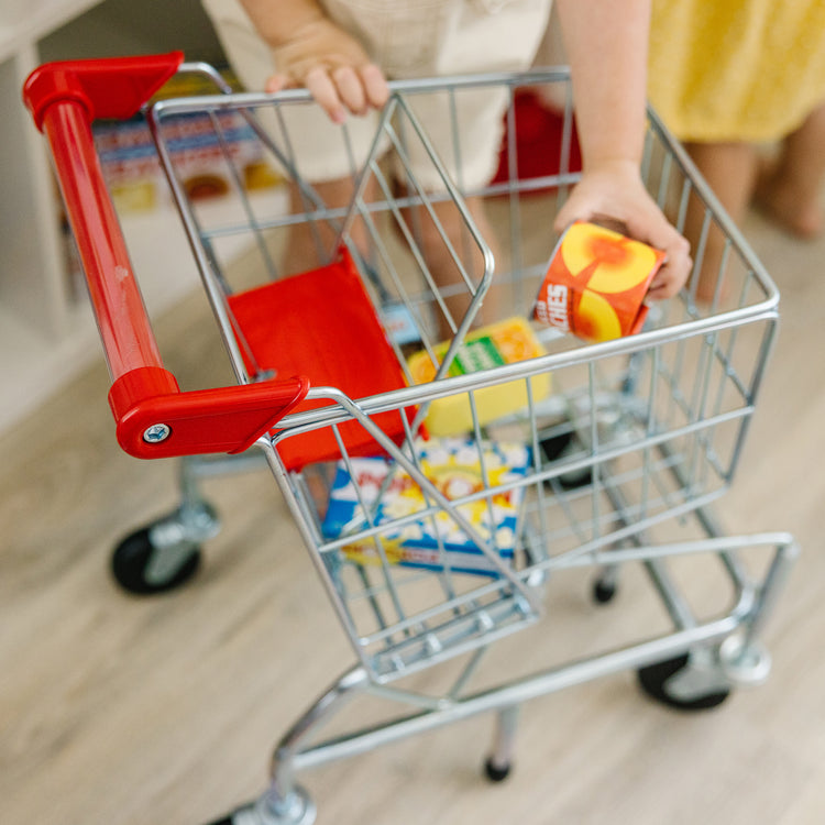 A kid playing with The Melissa & Doug Toy Shopping Cart With Sturdy Metal Frame