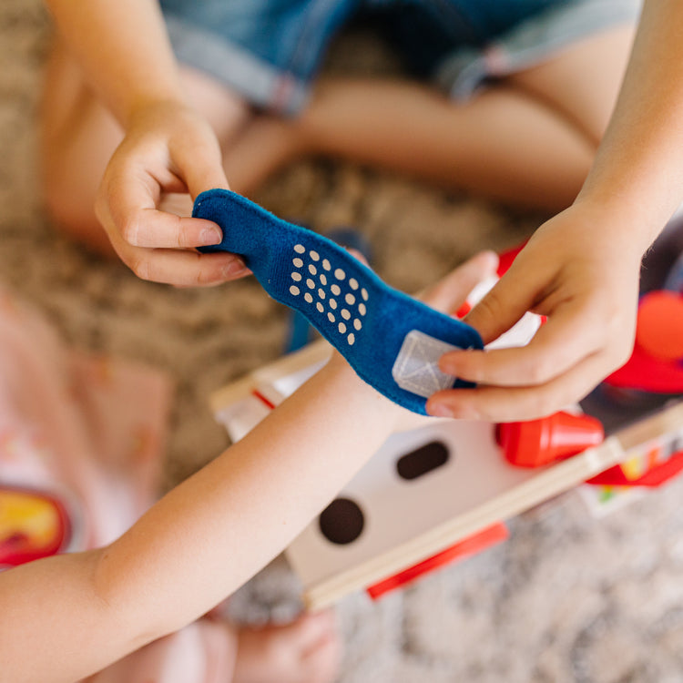 A kid playing with The Melissa & Doug PAW Patrol Marshall's Wooden Rescue EMT Caddy (14 Pieces)