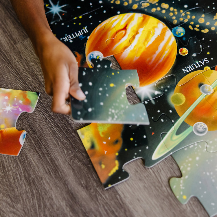 A kid playing with The Melissa & Doug Solar System Floor Puzzle (48 pcs, 2 x 3 Feet)