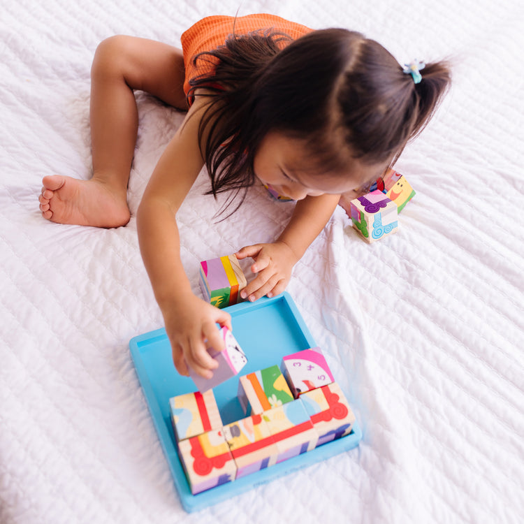 A kid playing with The Melissa & Doug Blue's Clues & You! Wooden Cube Puzzle (16 Pieces)