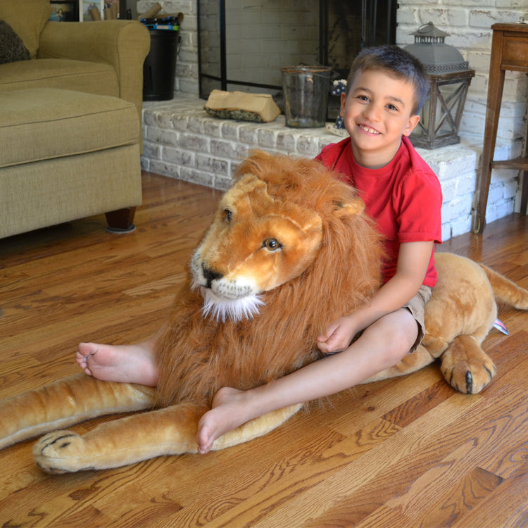 A kid playing with The Melissa & Doug Giant Lion - Lifelike Stuffed Animal (over 6 feet long)