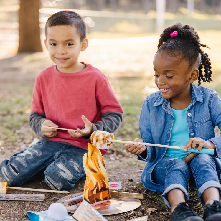 A kid playing with The Melissa & Doug Let's Explore Campfire S'Mores Play Set