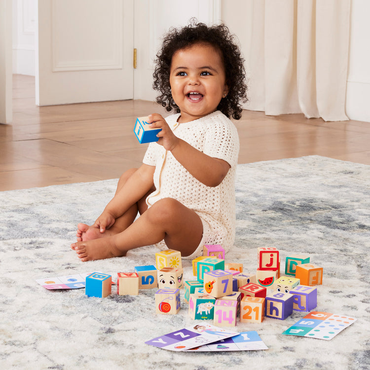 A kid playing with The Melissa & Doug Ms. Rachel Letter, Number, and Game Wooden Learning Blocks with Activity Cards for Girls and Boys Toddlers Ages 18 Months+