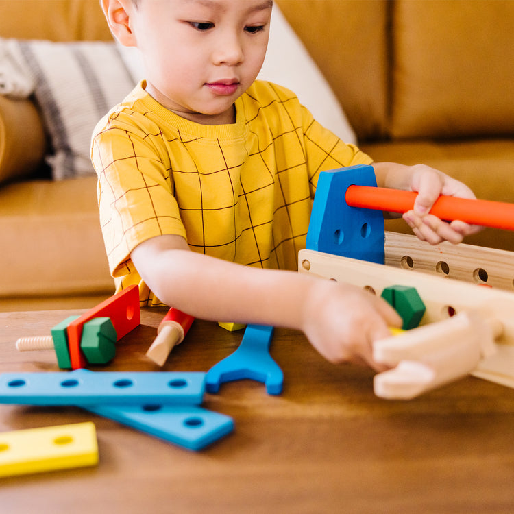 A kid playing with The Melissa & Doug Take-Along Tool Kit Wooden Construction Toy (24 pcs)