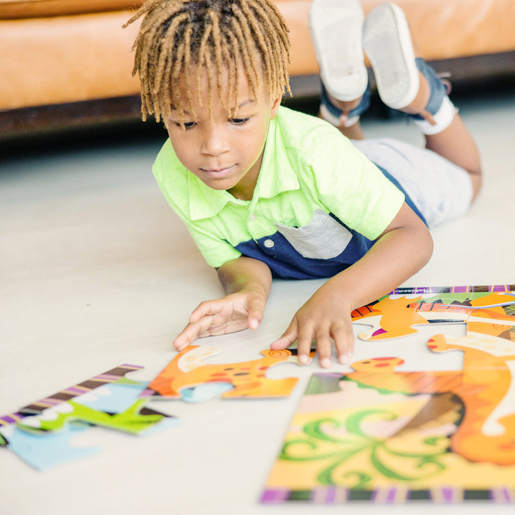 A kid playing with The Melissa & Doug Dinosaur Dawn Jumbo Jigsaw Floor Puzzle (24 pcs, 2 x 3 feet)