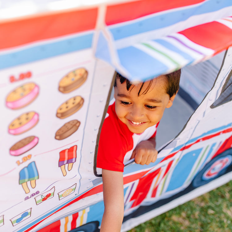 A kid playing with The Melissa & Doug Fabric Double-Sided Food Truck Play Tent - Ice Cream And BBQ