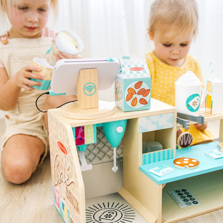 A kid playing with The Melissa & Doug Wooden Café Barista Coffee Shop (35 Pieces)