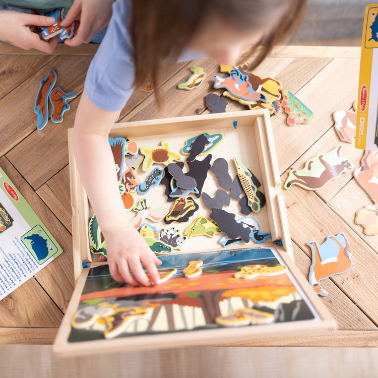 A kid playing with The Melissa & Doug National Parks Wooden Picture Matching Magnetic Game