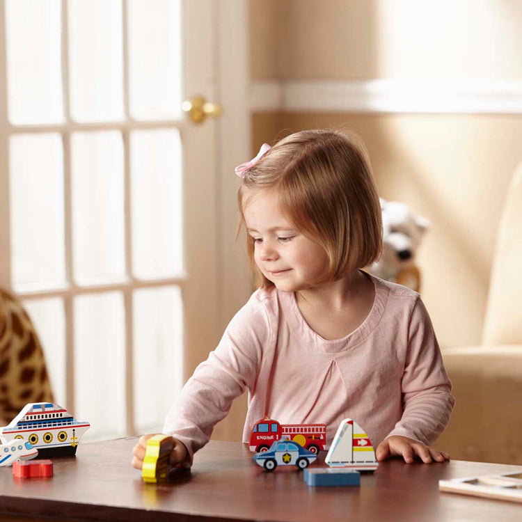 A kid playing with The Melissa & Doug Vehicles Wooden Chunky Puzzle - Plane, Train, Cars, and Boats (9 pcs)