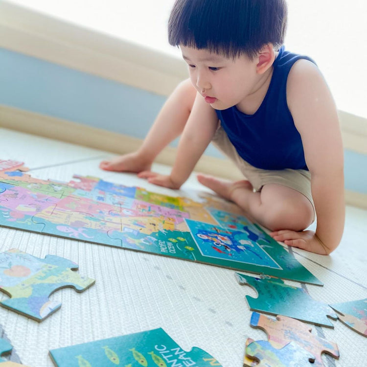 A kid playing with The Melissa & Doug Natural Play Giant Floor Puzzle: America the Beautiful (60 Pieces)