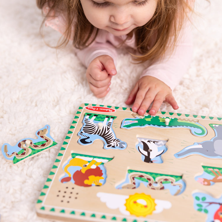 A kid playing with The Melissa & Doug Zoo Animals Sound Puzzle - Wooden Peg Puzzle With Sound Effects (8 pcs)