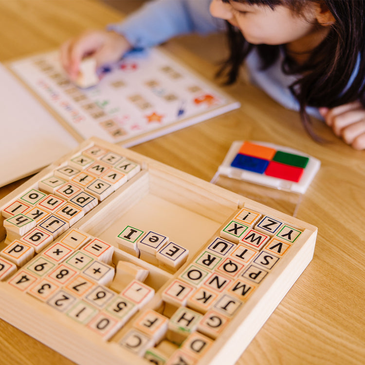 A kid playing with The Melissa & Doug Deluxe Letters and Numbers Wooden Stamp Set ABCs 123s With Activity Book, 4-Color Stamp Pad