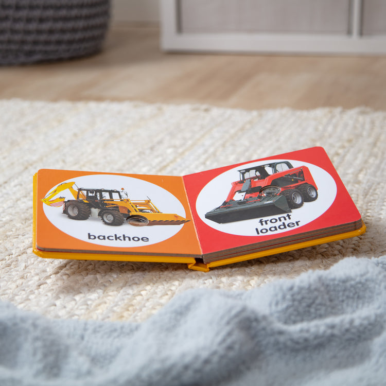 A playroom scene with The Melissa & Doug Children’s Book – Poke-a-Dot: Construction Vehicles (Board Book with Buttons to Pop)