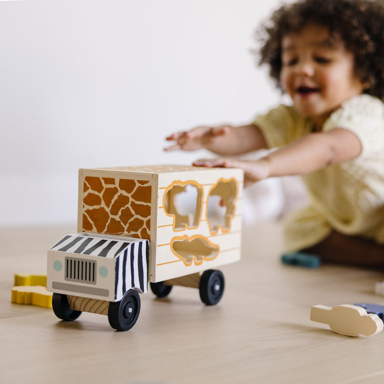 A kid playing with The Melissa & Doug Animal Rescue Shape-Sorting Truck - Wooden Toy With 7 Animals and 2 Play Figures